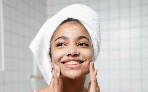 Woman applying moisturizer to her face, highlighting effective skincare for dry skin